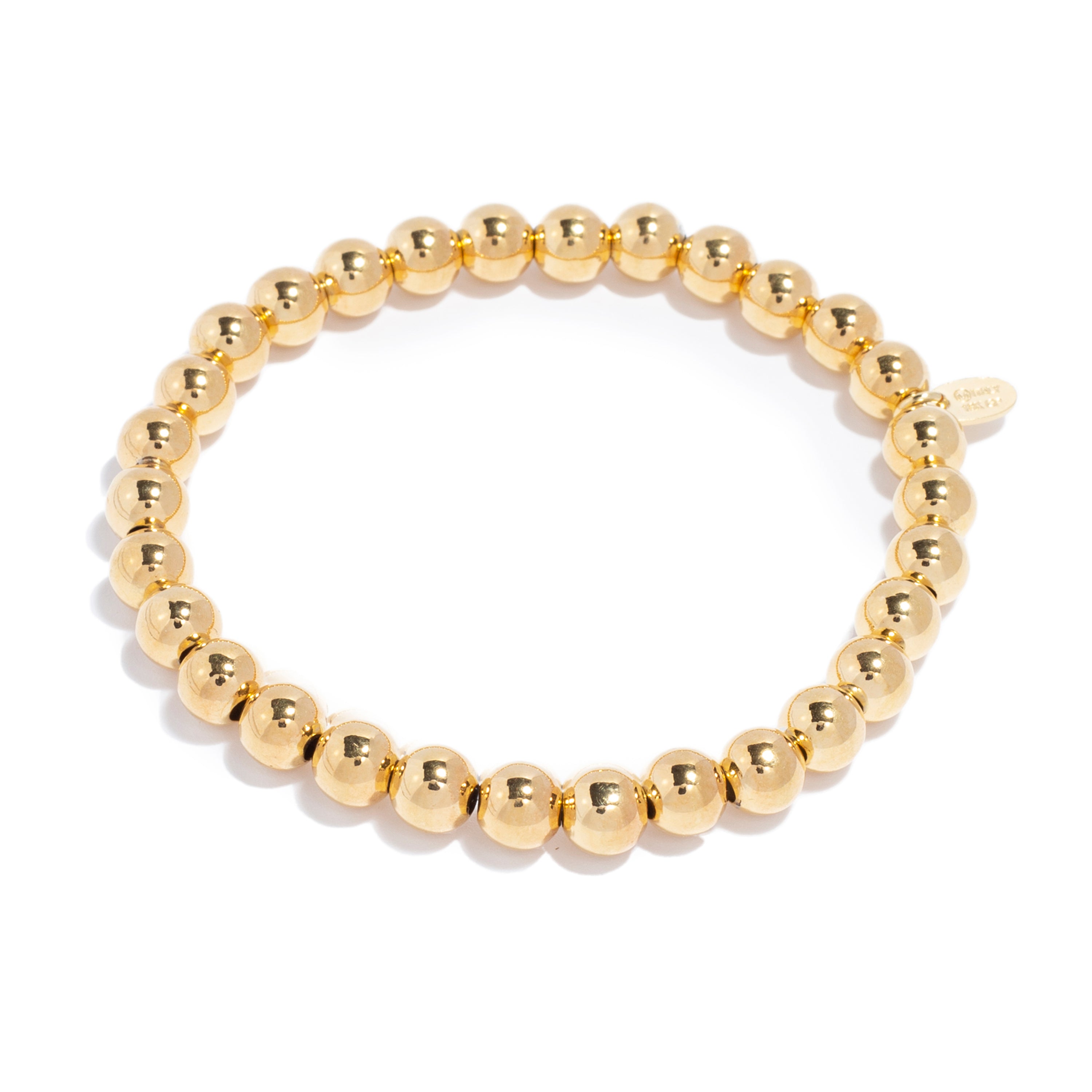 Close-up of a stretchy gold bead bracelet made of shiny, round beads strung together.