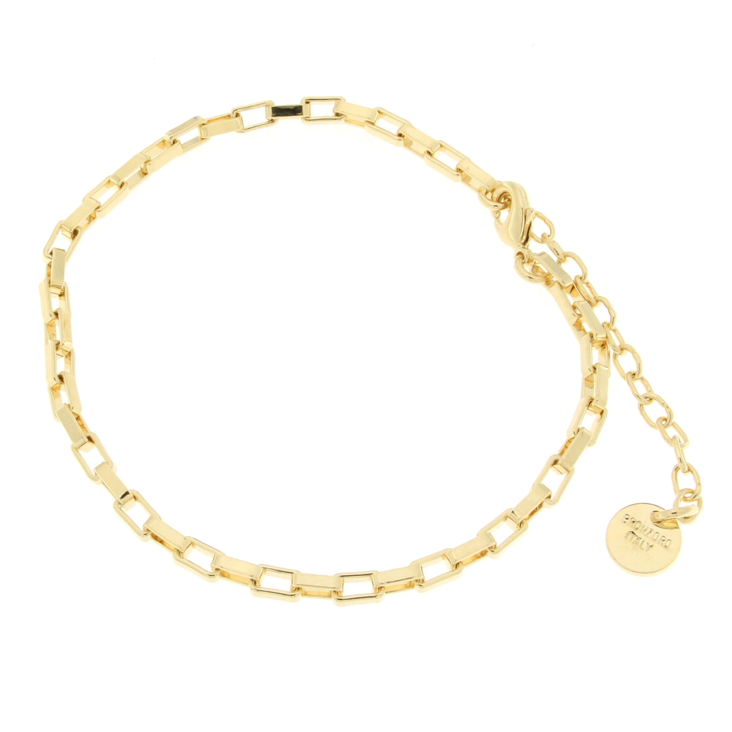 A stylish gold anklet featuring a unique design with alternating rectangular and square links. The anklet is secured with a lobster clasp and includes a delicate extension chain for adjustable sizing, accompanied by a small circular charm that features a logo.