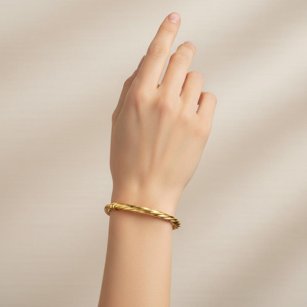 Twisted gold oval bangle on model's wrist